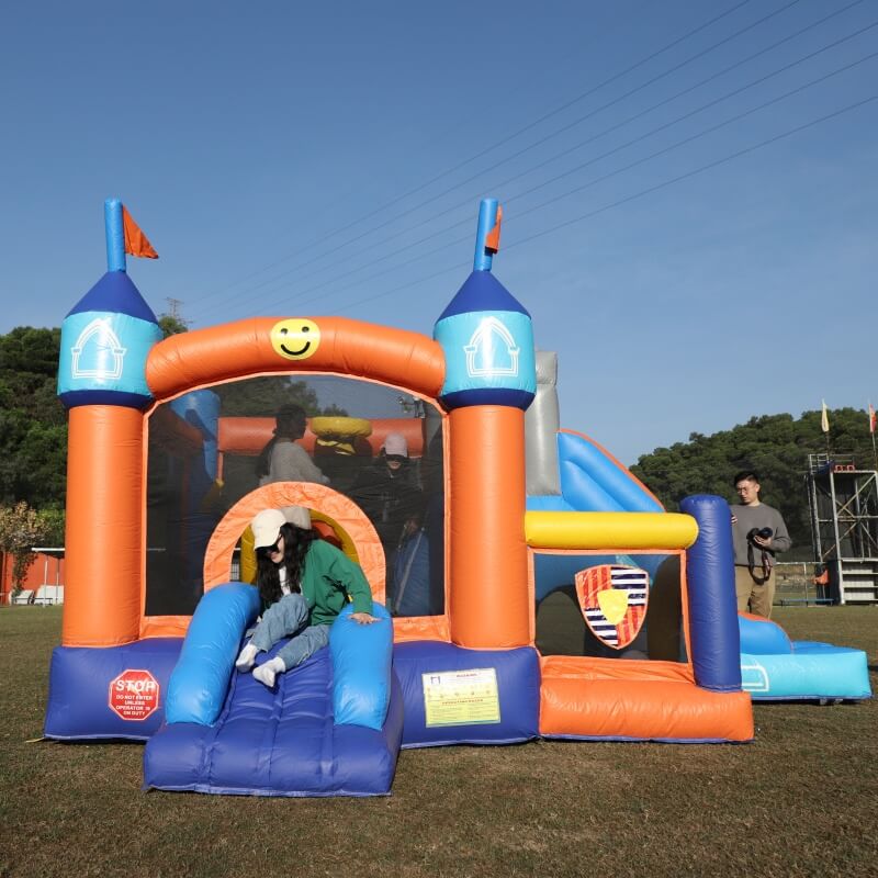 adults playing on an inflatable castle in a grassy area with a clear blue sky |bouncinlife